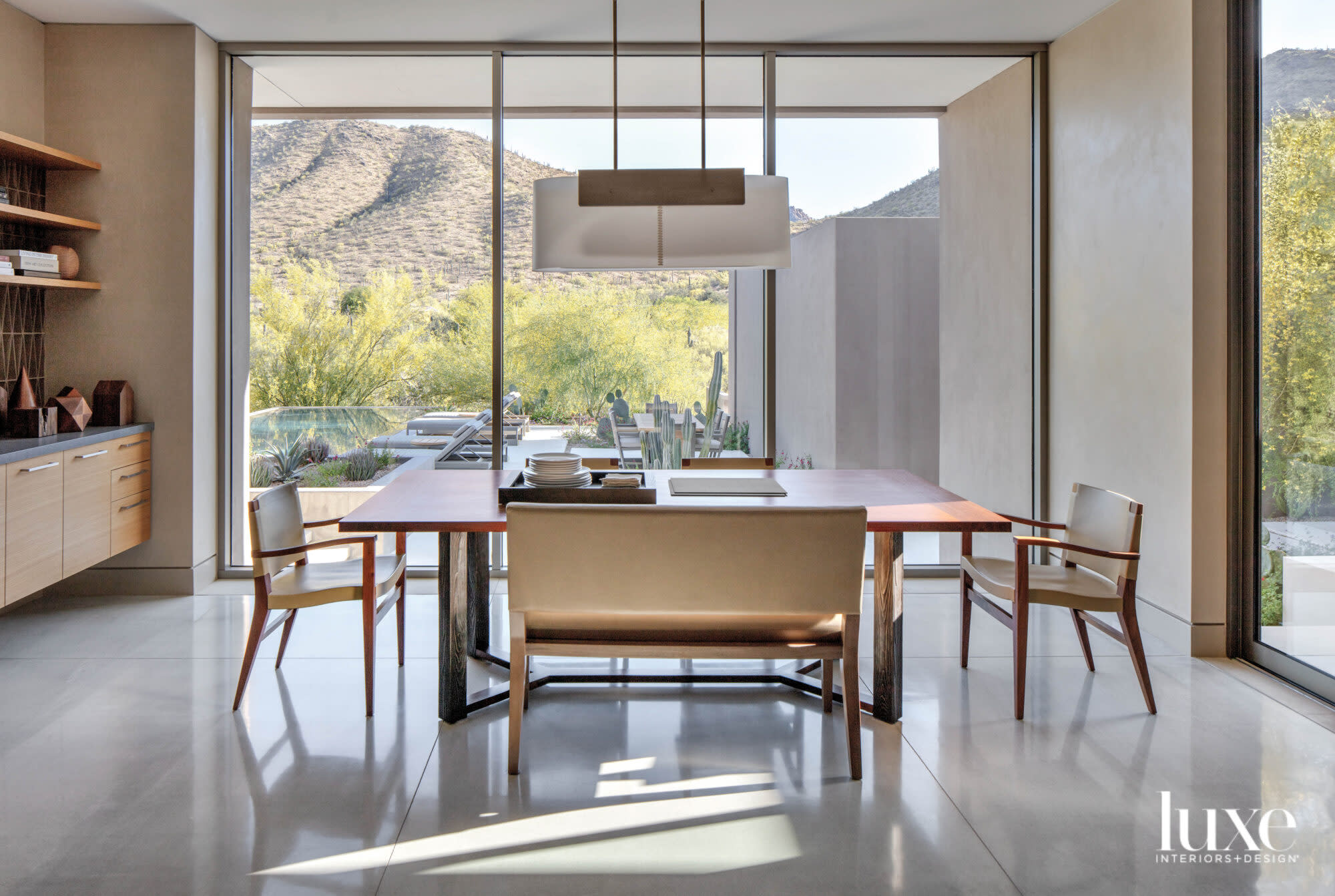 A breakfast nook with minimalist furniture and floor-to-ceiling window that look out on a mountain.s