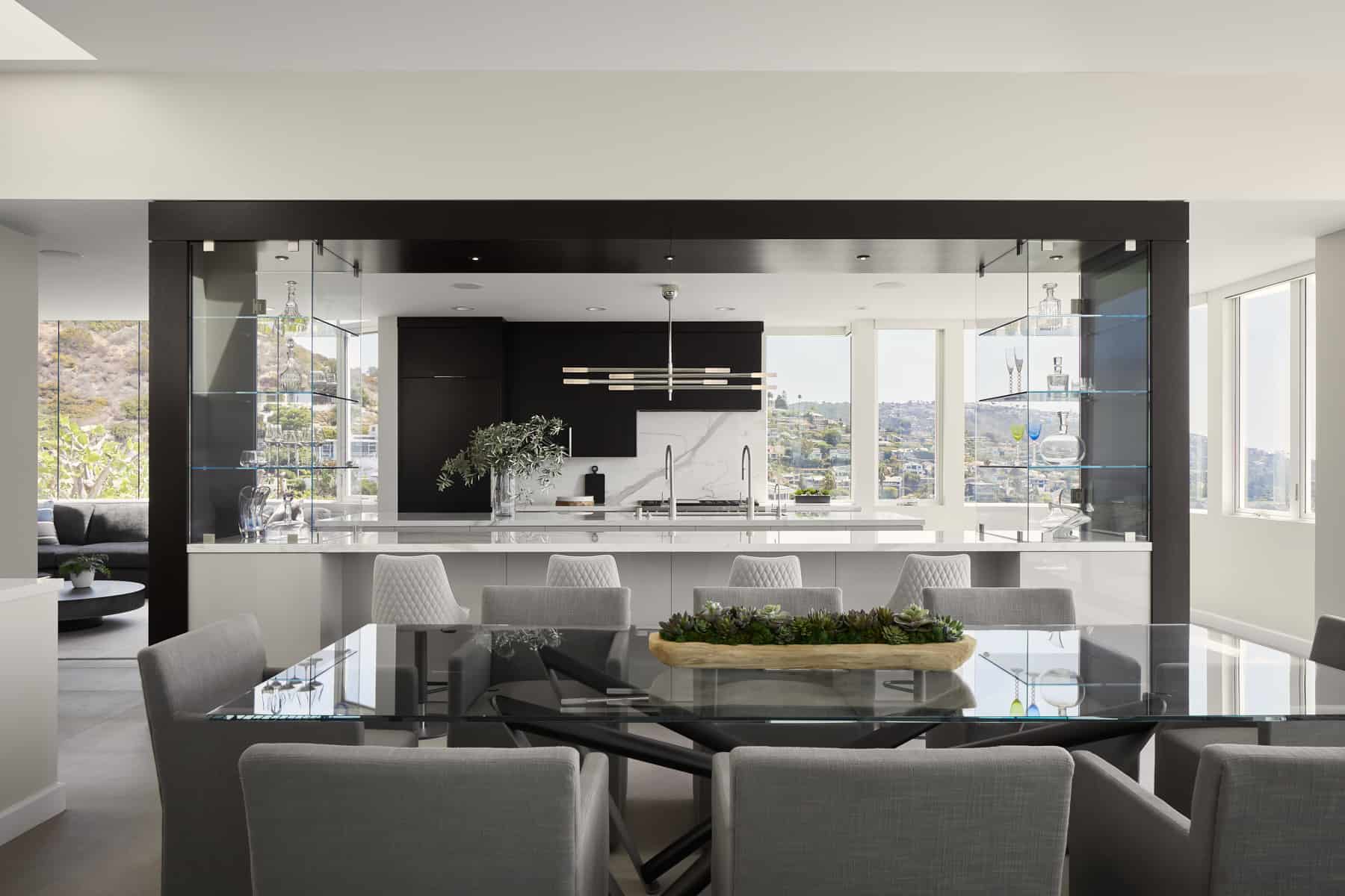  A sleek modern kitchen in Southern California by Payton Addison Interior Design featuring a dining table surrounded by chairs, showcasing contemporary design elements. 