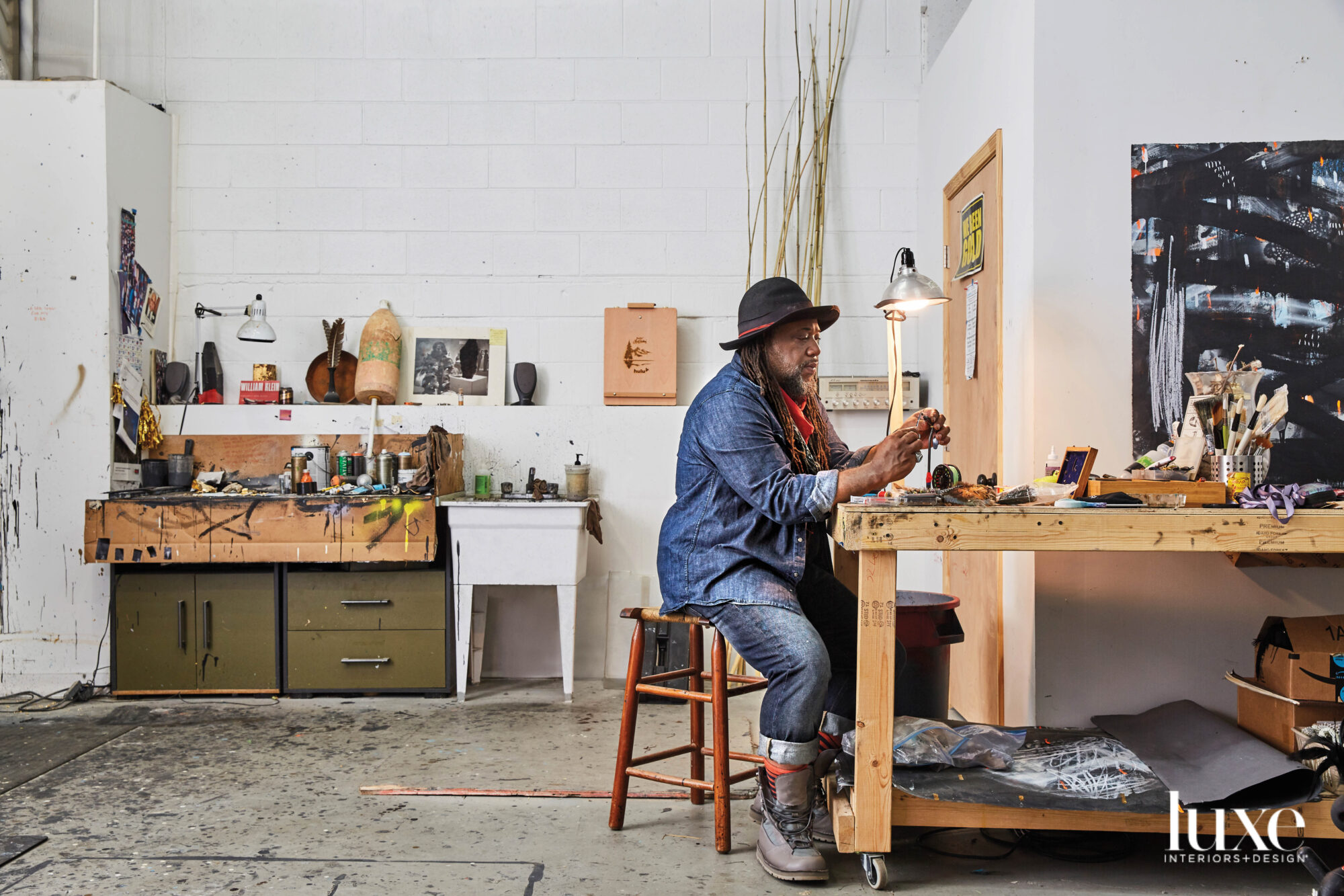 Man sitting on stool at workshop desk in studio, working with his hands