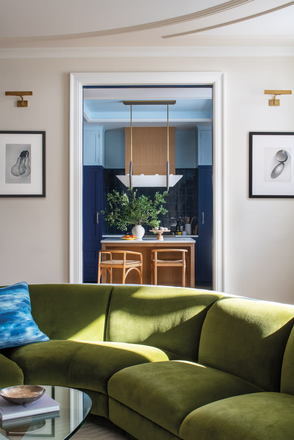modern entryway with a green sofa and a blue kitchen seen through the doorway