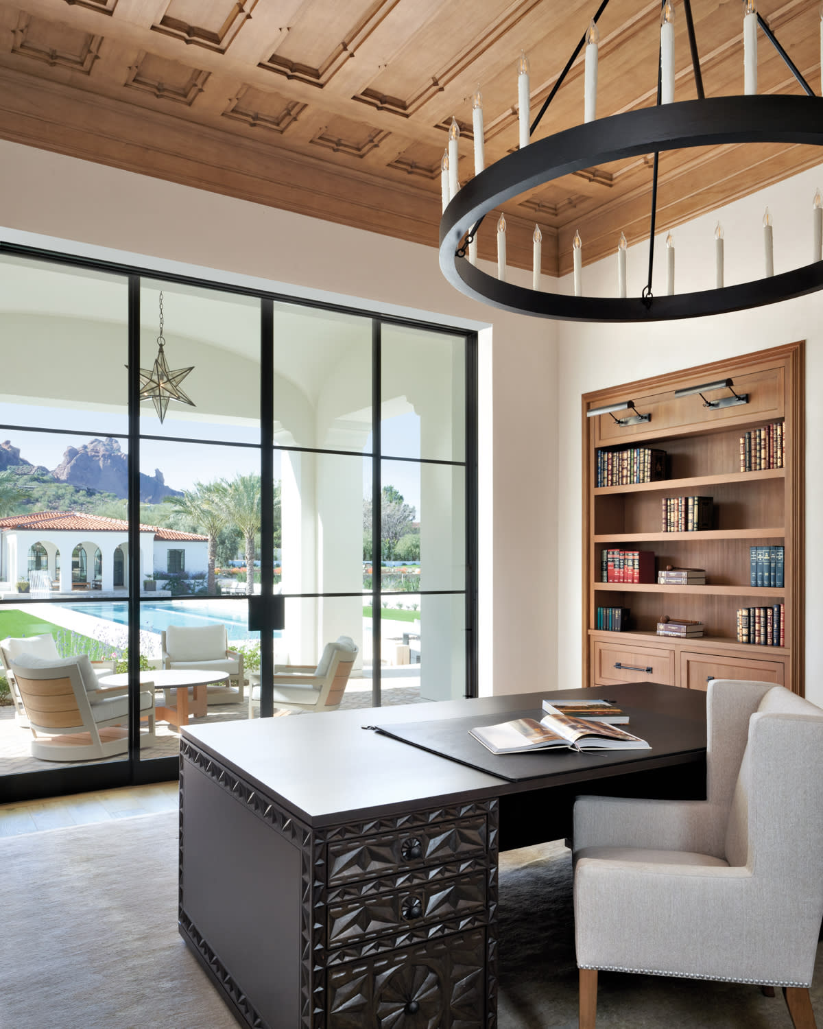 library with wood-paneled ceilings, built-in shelving and a large dark wood desk