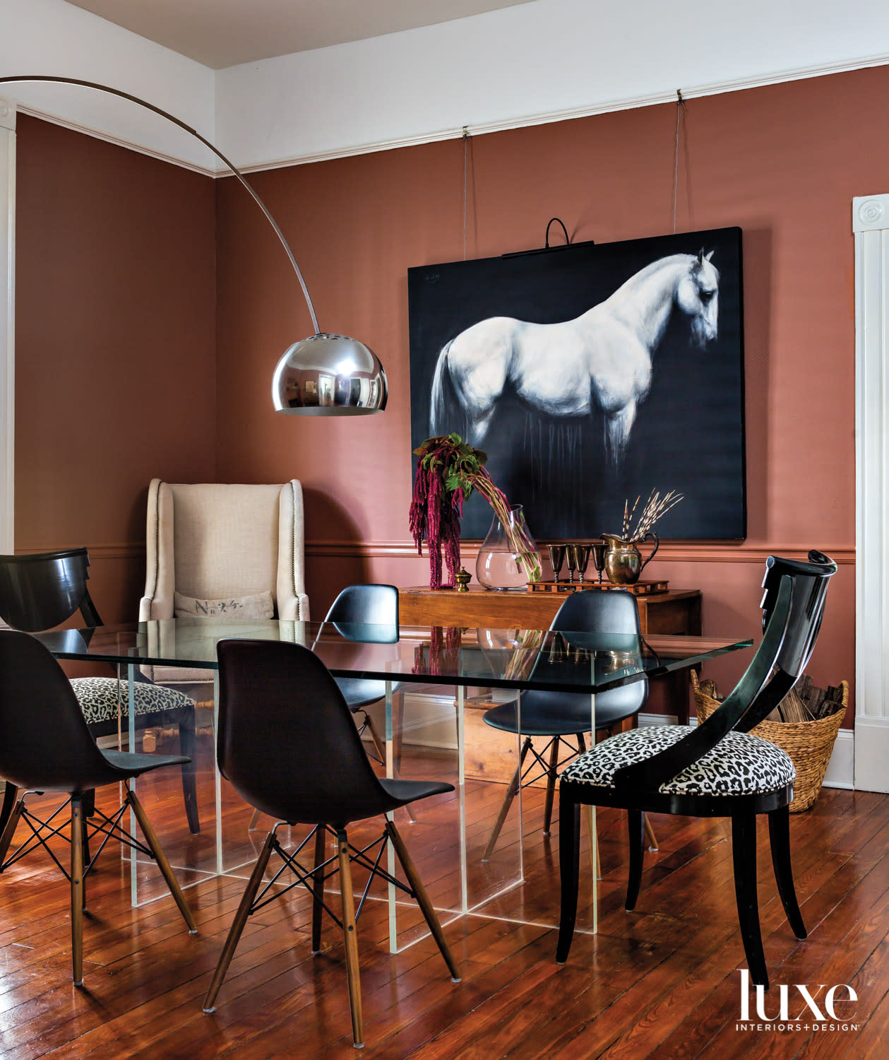 Dining room with terra cotta walls, modern dining table, arc lamp and large equine artwork