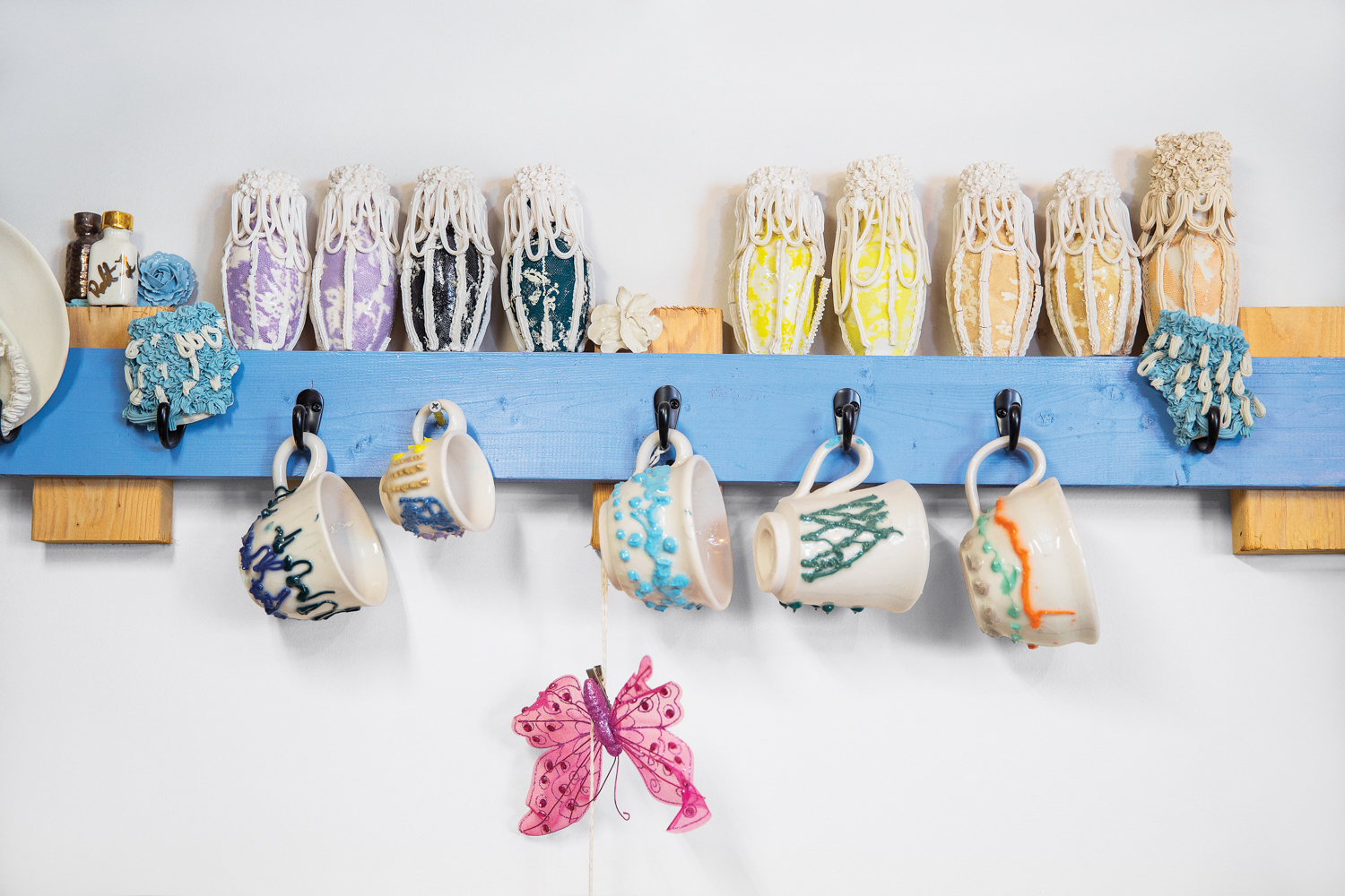 Shelf with small vessels and coffee cups on hooks