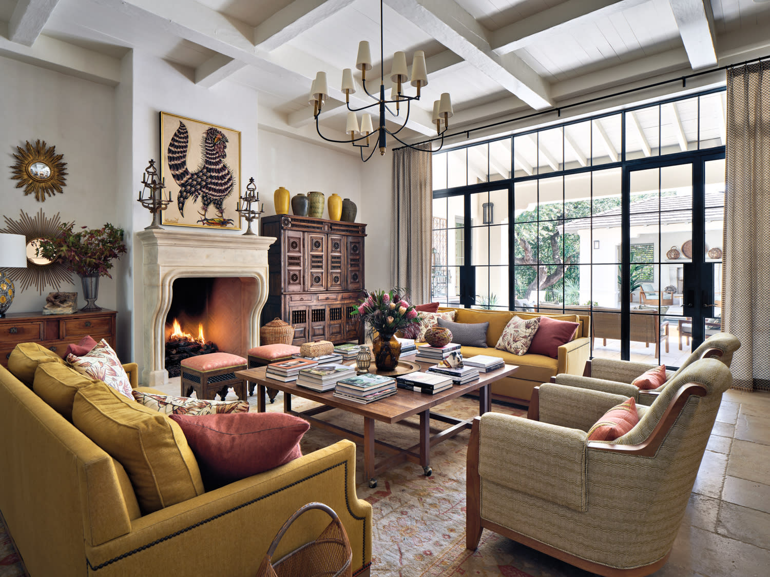 Living room colorful sofas, brown coffee table, illuminating chandelier and rooster tapestry above the fireplace