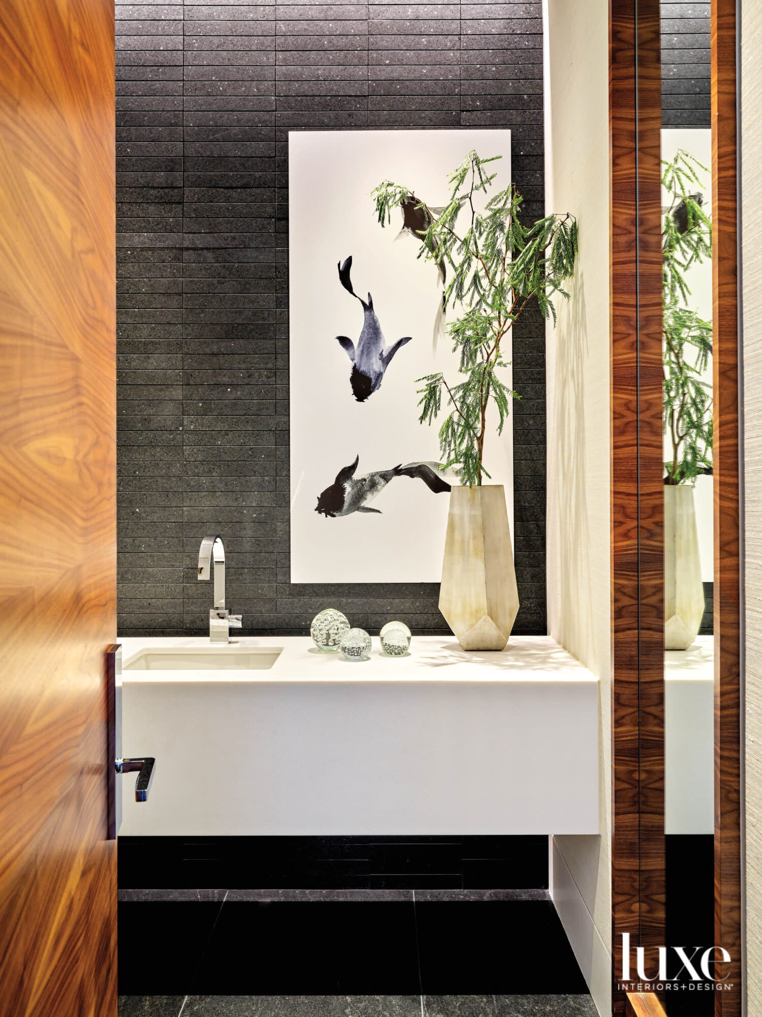 A powder room with black stone walls, black granite floors and a floating white vanity.