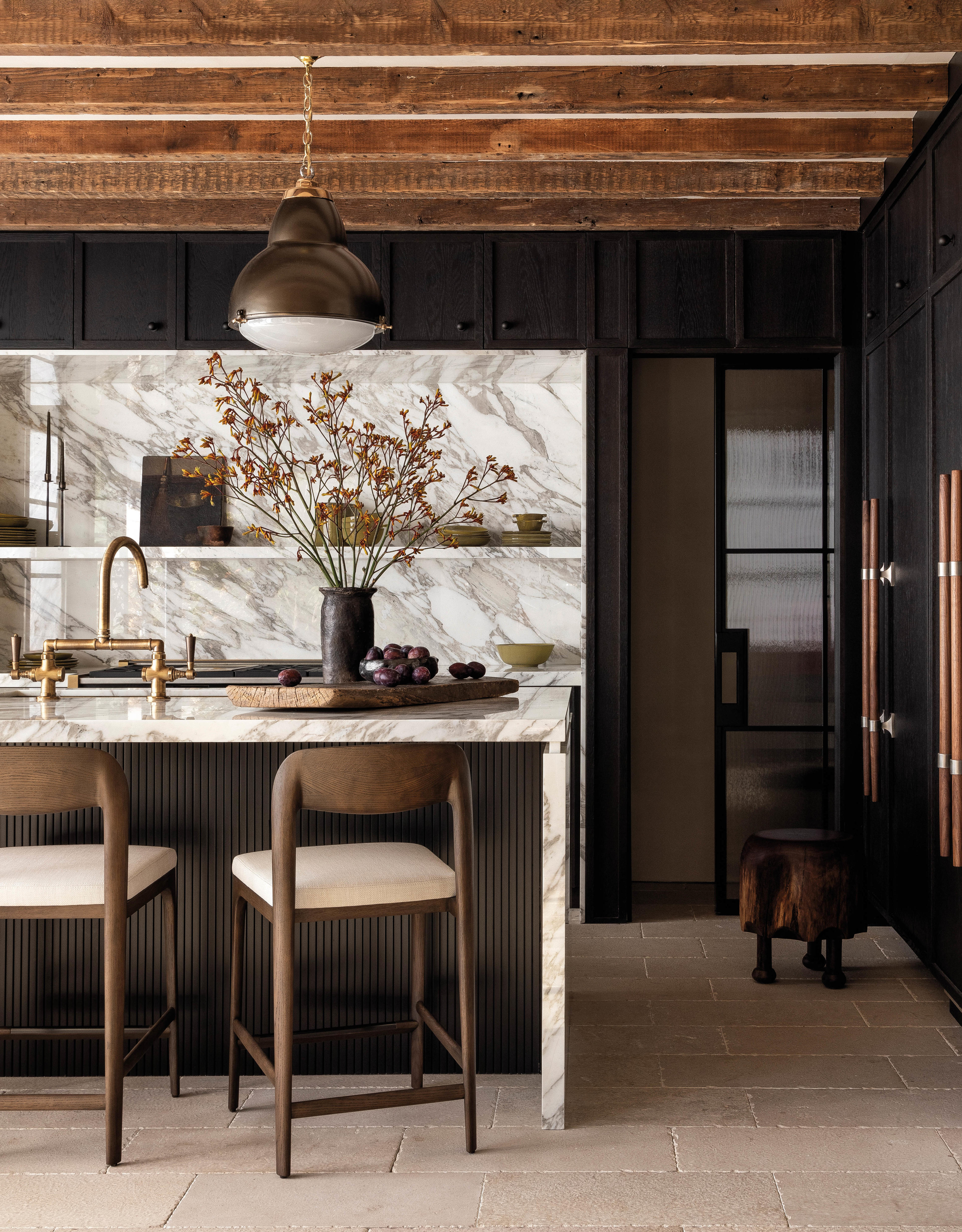 chef's kitchen with a marble-topped island and backsplash, brass plumbing fixtures and exposed beams