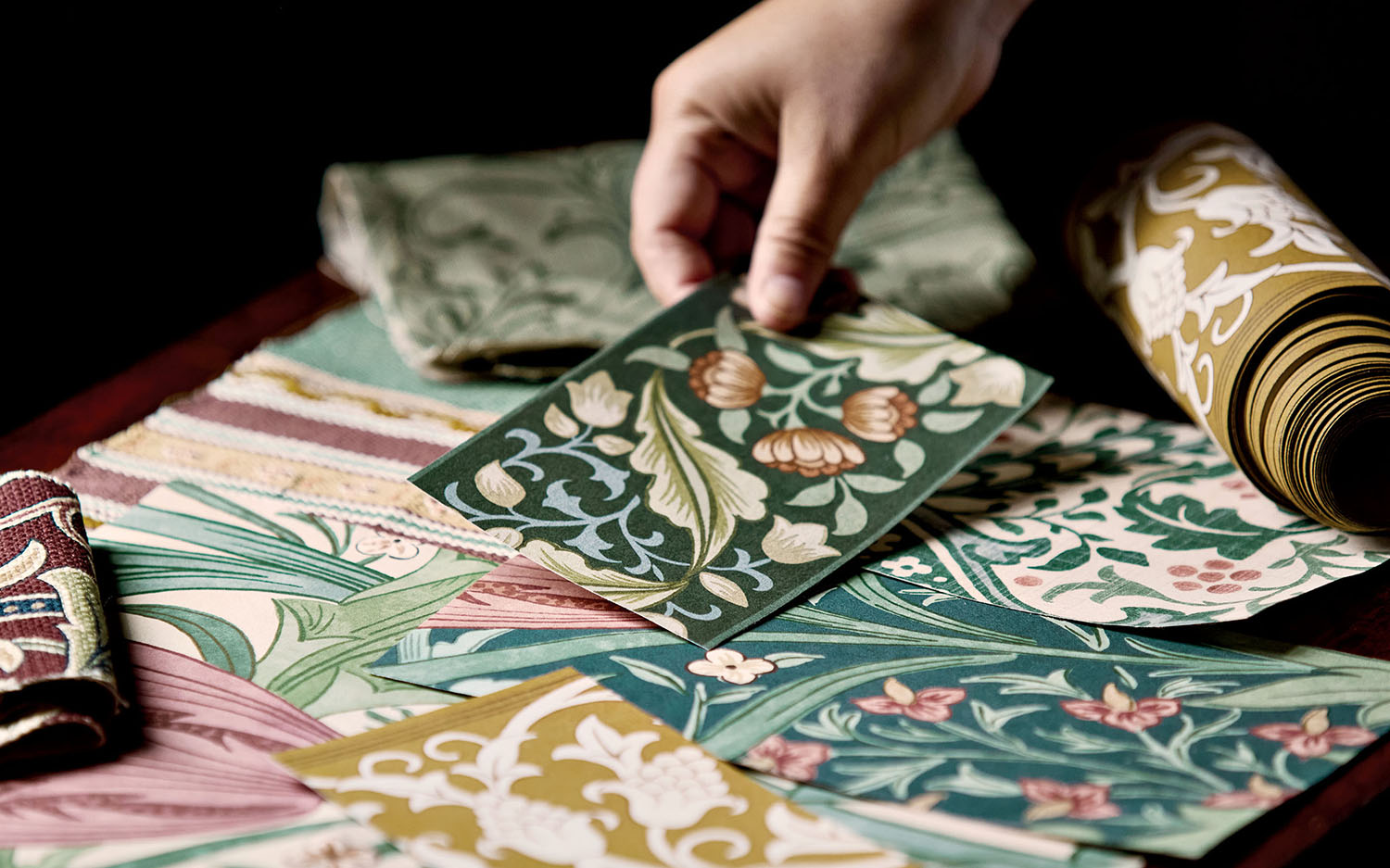 a person reaches for a sample on a table of Morris & Co.'s Unfinished Works collection