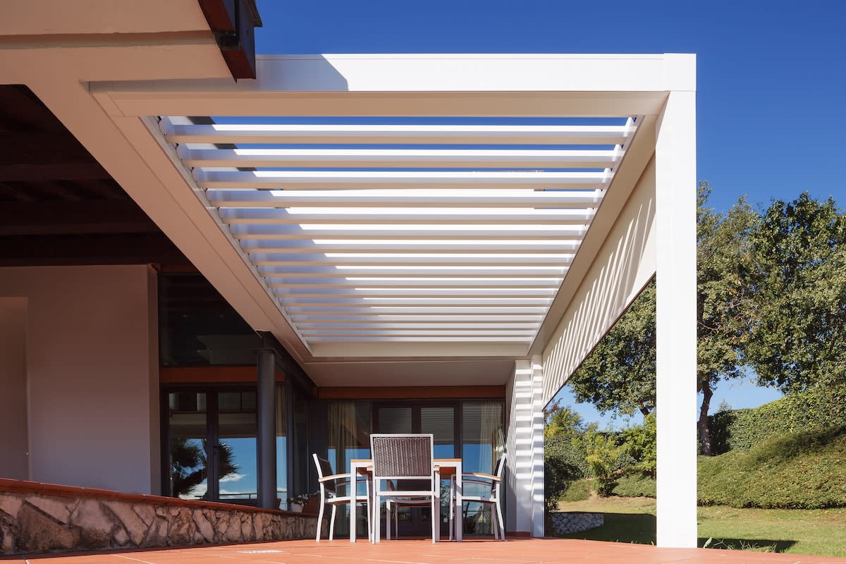 A serene patio scene showcasing a white pergola and comfortable chairs for outdoor enjoyment.