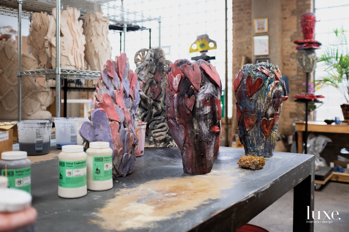 black sculptures with pink and blue accessories, and glue on a black wooden table