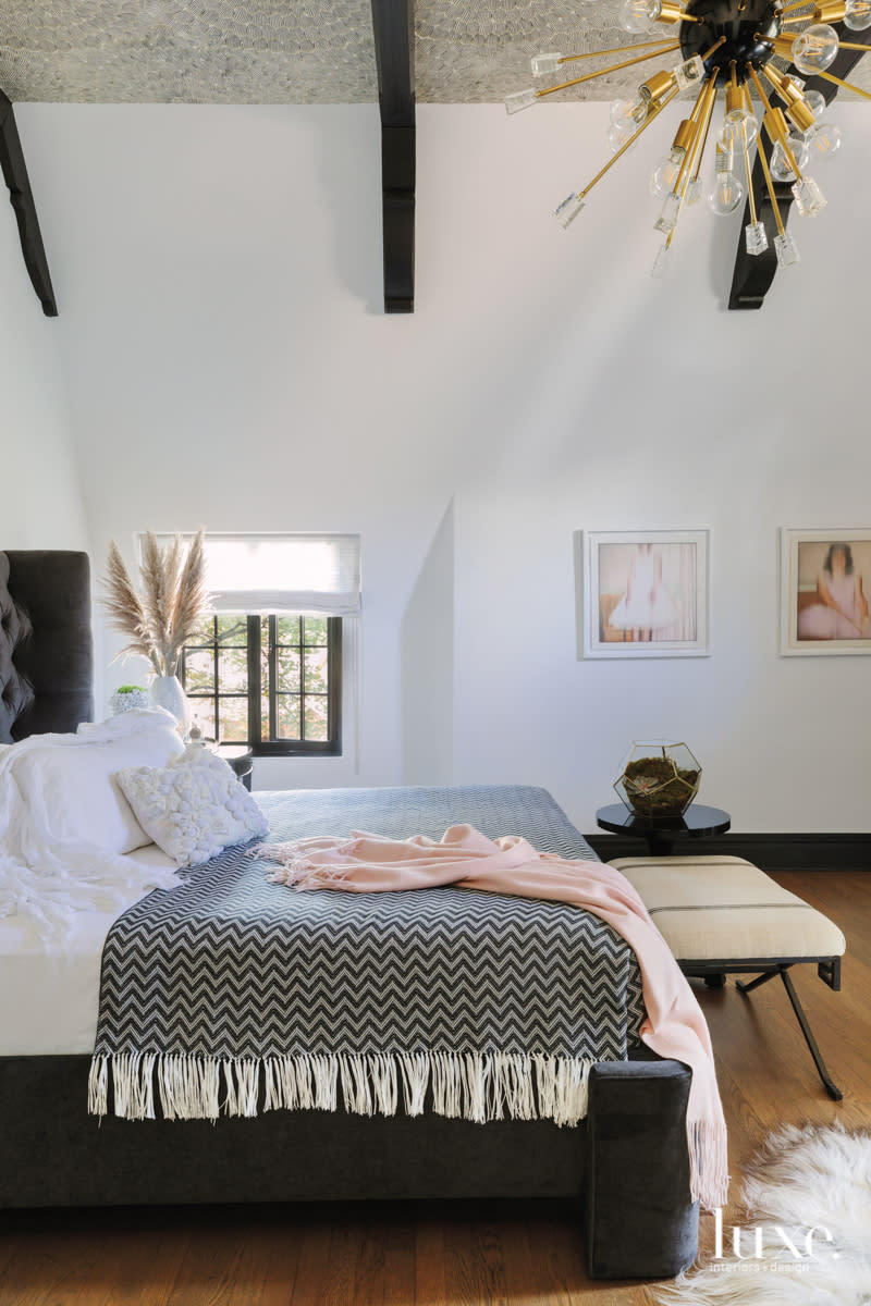 The guest room has dark wood beams and wallpaper on the ceiling.