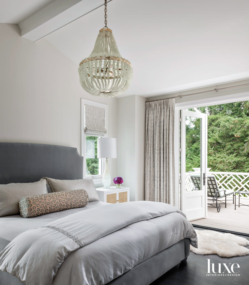 Main bedroom with upholstered bed, chandelier, and terrace outside