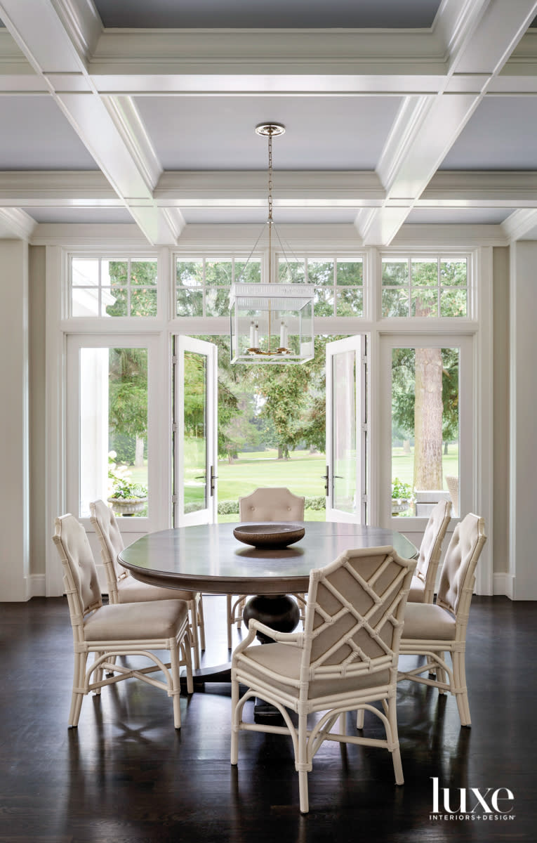 Dining room with faux bamboo style chairs and door opening to landscaping