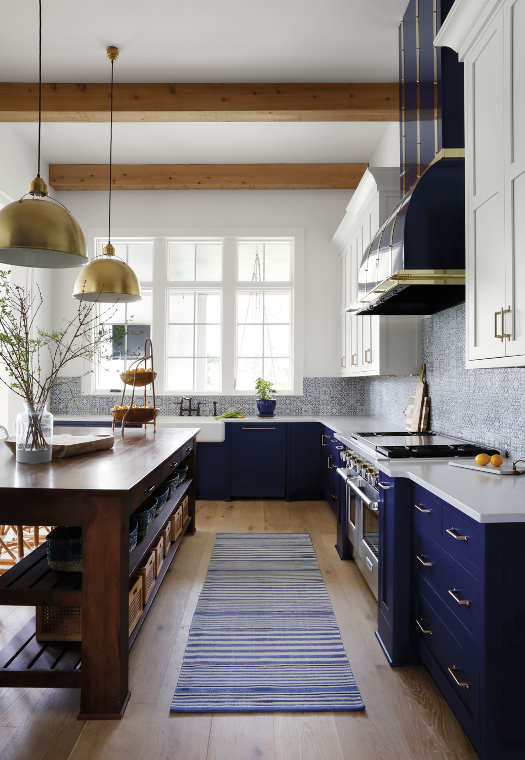 Rustic kitchen with dark blue cabinetry, striped rug and brass accents