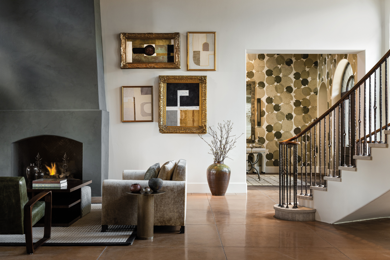 staircase descending into a living room with a floor-to-ceiling stone fireplace and a foyer beyond