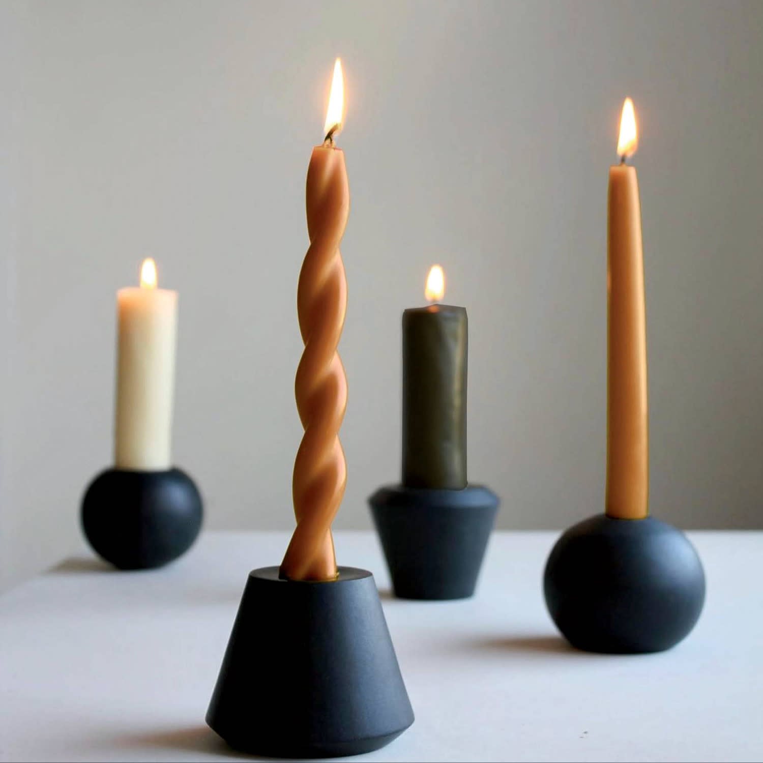 Candlesticks of varying lengths and colors sit in angular holders.