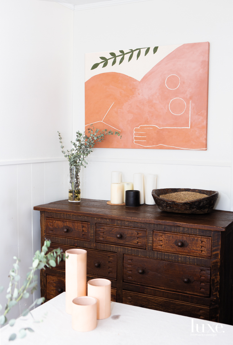 rf alvarez's work of a nude body and branch is featured on a wall above a brown wood table