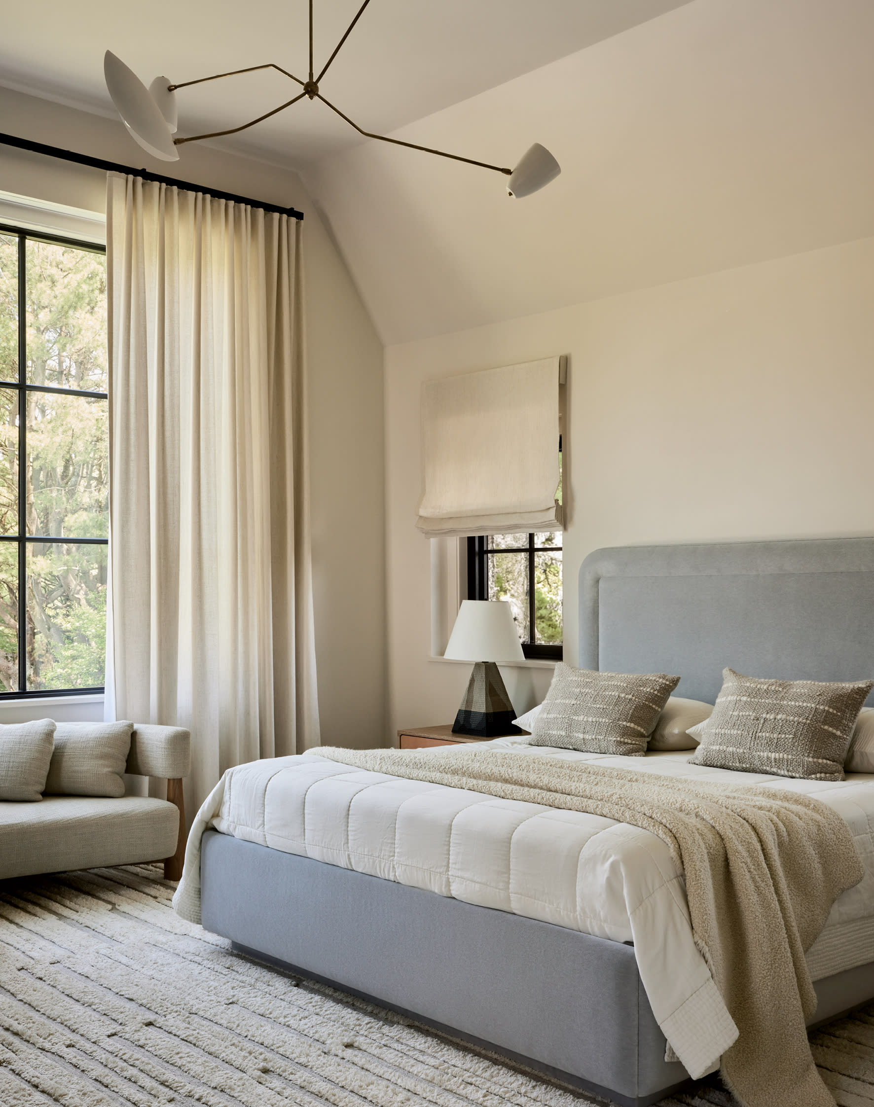 contemporary bedroom with a light grey upholstered bed and cream colored walls