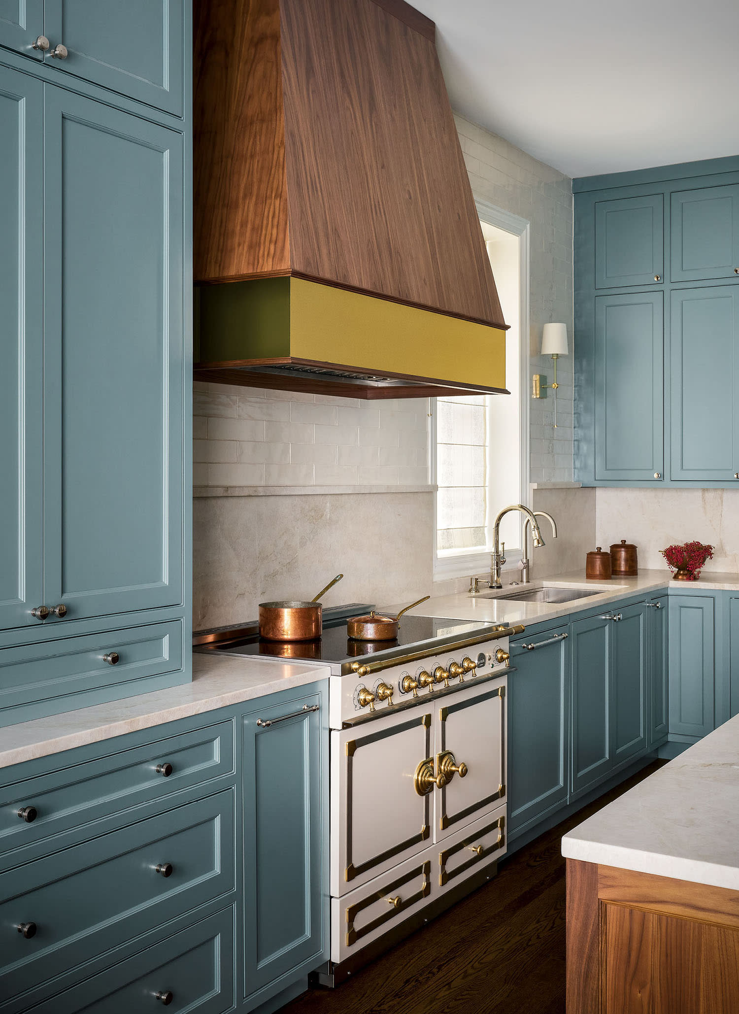 Blue cabinetry in a kitchen with white counters, a sink and white tile backsplash behind the stove.