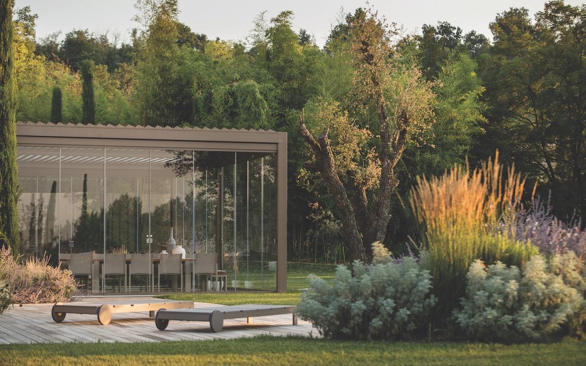 A modern garden featuring a glass wall and wooden benches, creating a serene and inviting outdoor space.