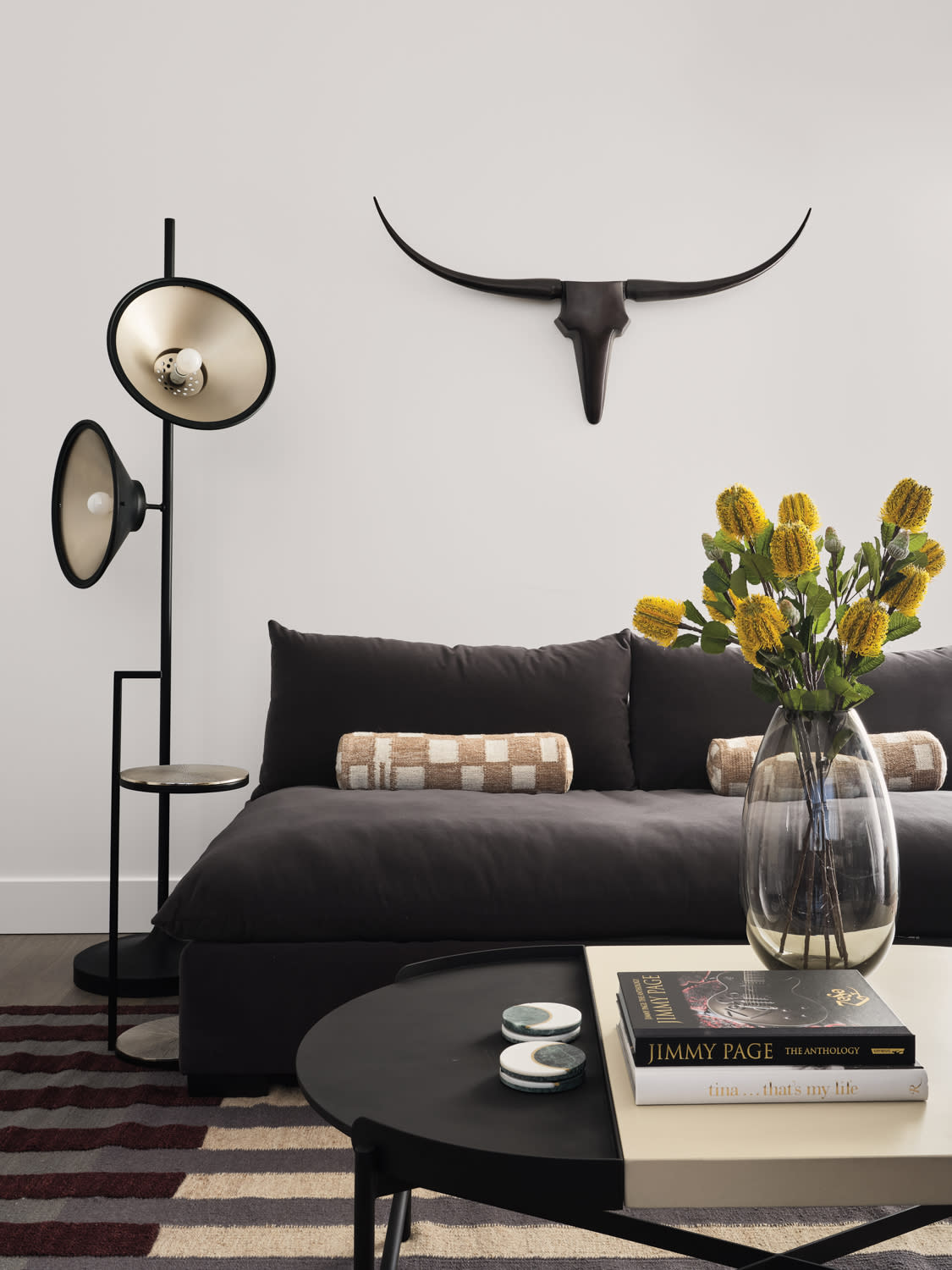 Cow's skull wall decor above a black sofa paired with black-and-gold floor lamp and coffee table