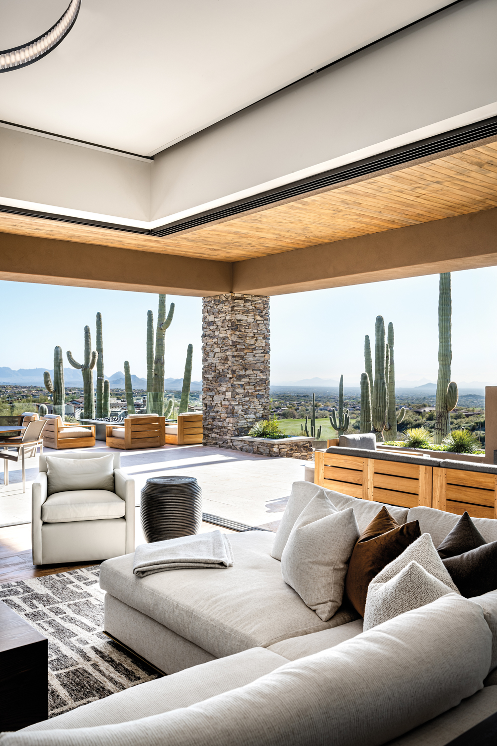 White sectional and armchair in a living room that opens to a patio surrounded by cacti in home by Holly Wright