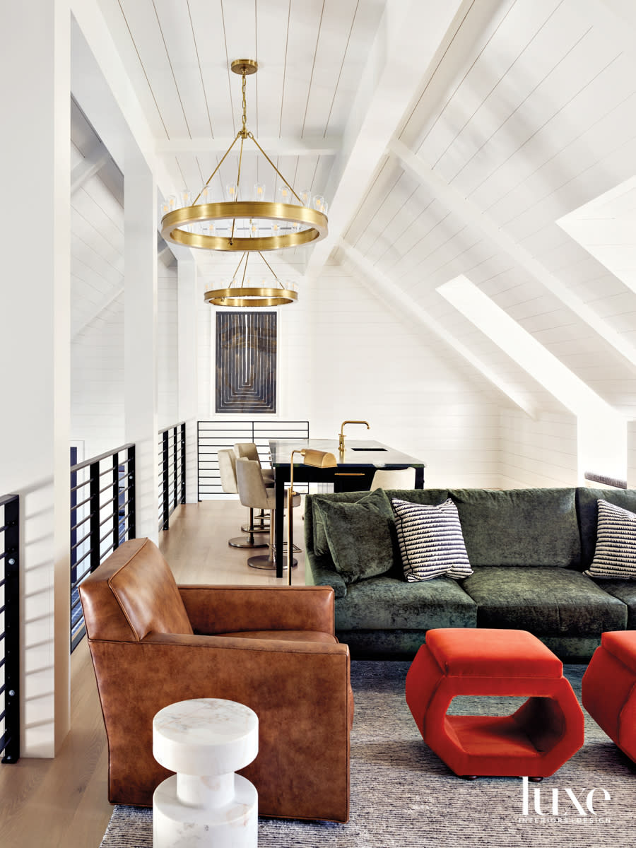 Upstairs loft game room with rafters painted white, plush upholstery and a modern leather club chair