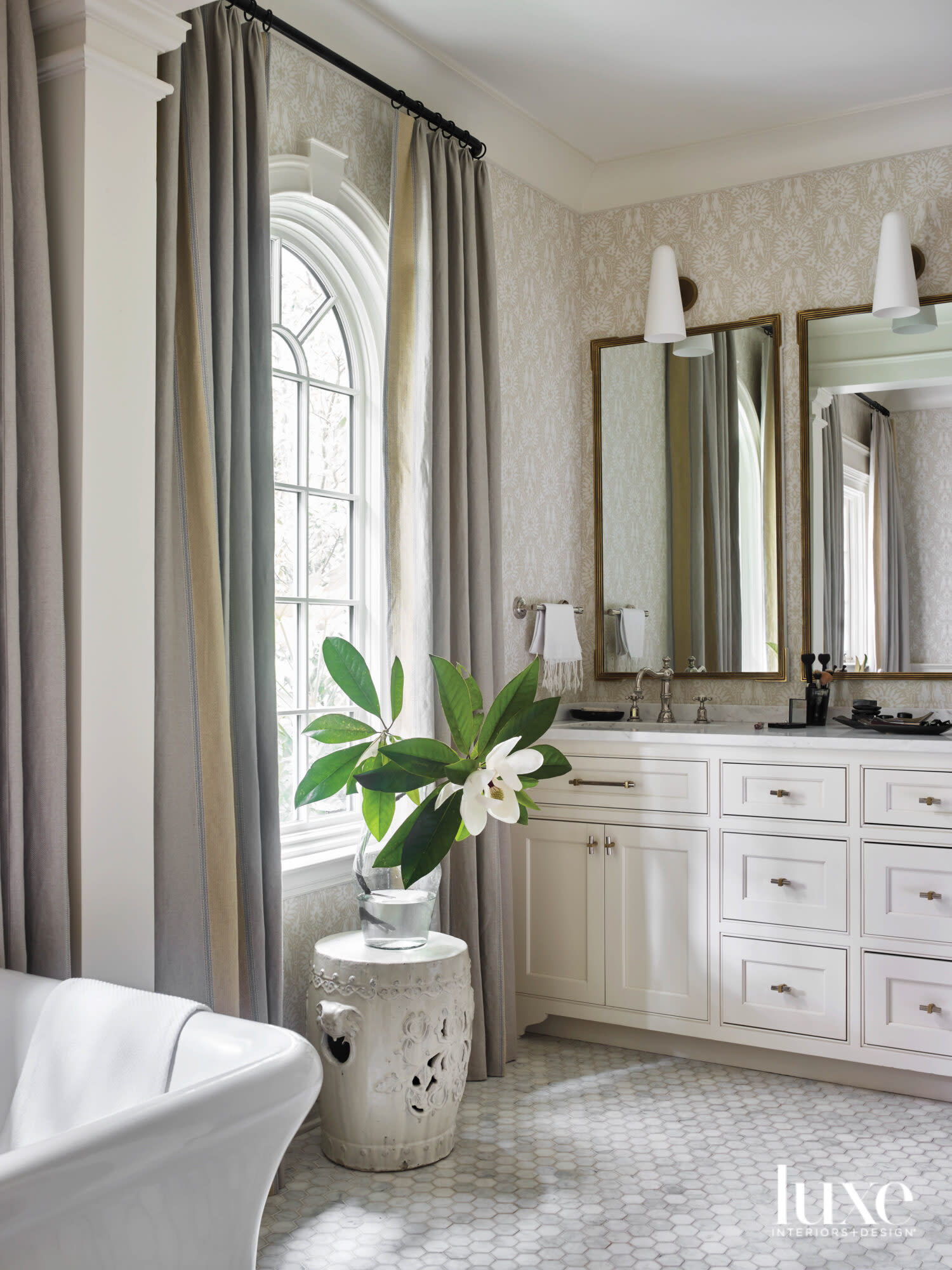 Softly lit bathroom with dramatic windows, soaking tub, double-mirror vanity and neutral palette