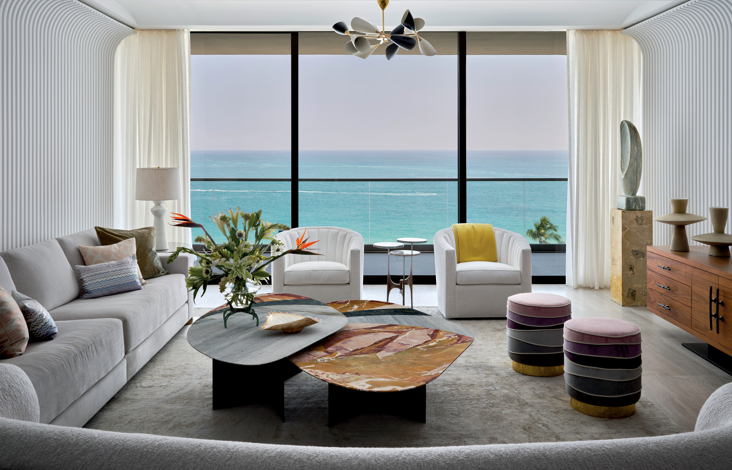 modern living room with nesting tables and sheer curtains framing ocean views