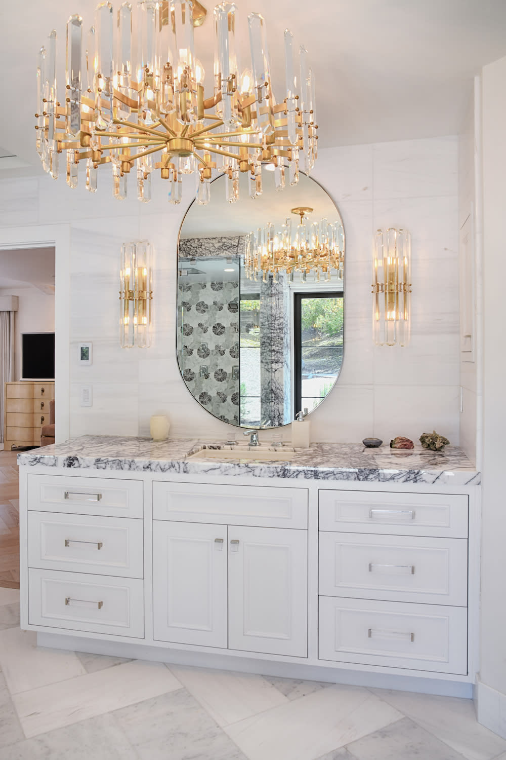 Luxurious bathroom with gold chandelier and marble countertops.