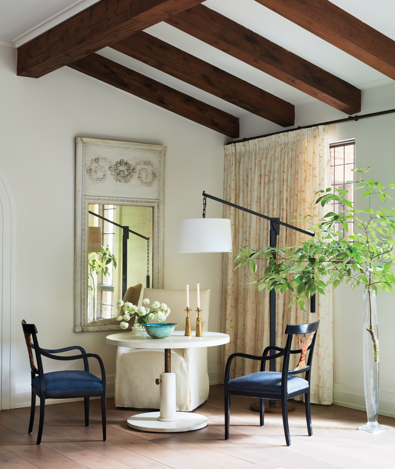 Breakfast nook with antique mirror, articulating floor lamp and wood ceiling beams