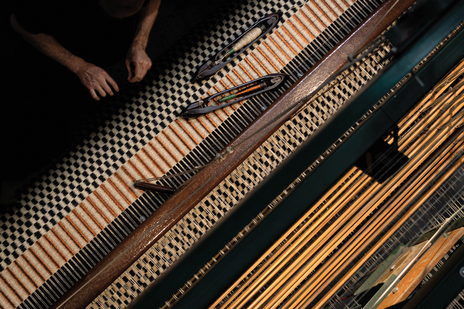 layers of differing checkered and striped textiles with hands nearby