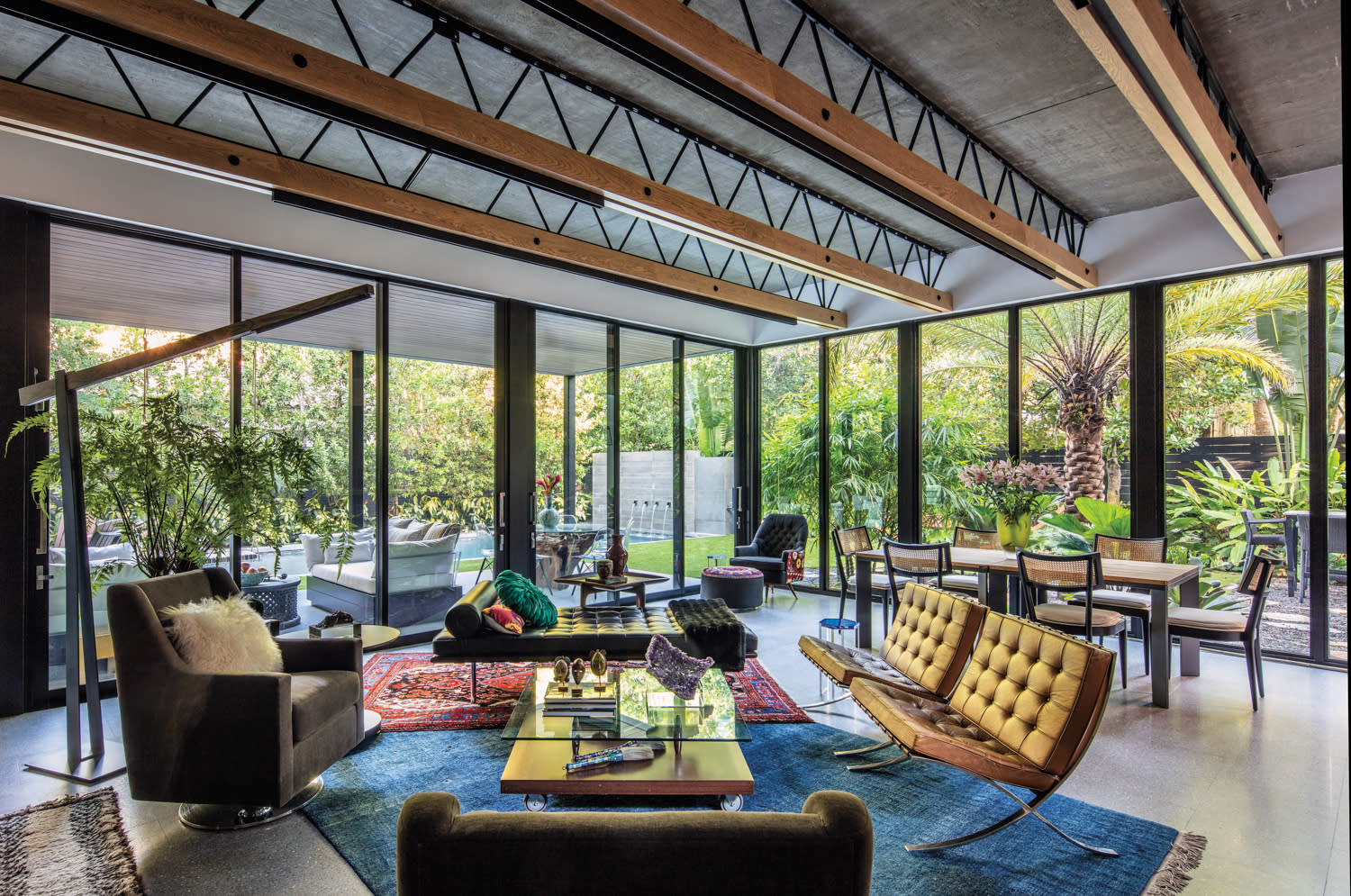 great lounge room with mix of seating, overlapping rugs and glass walls