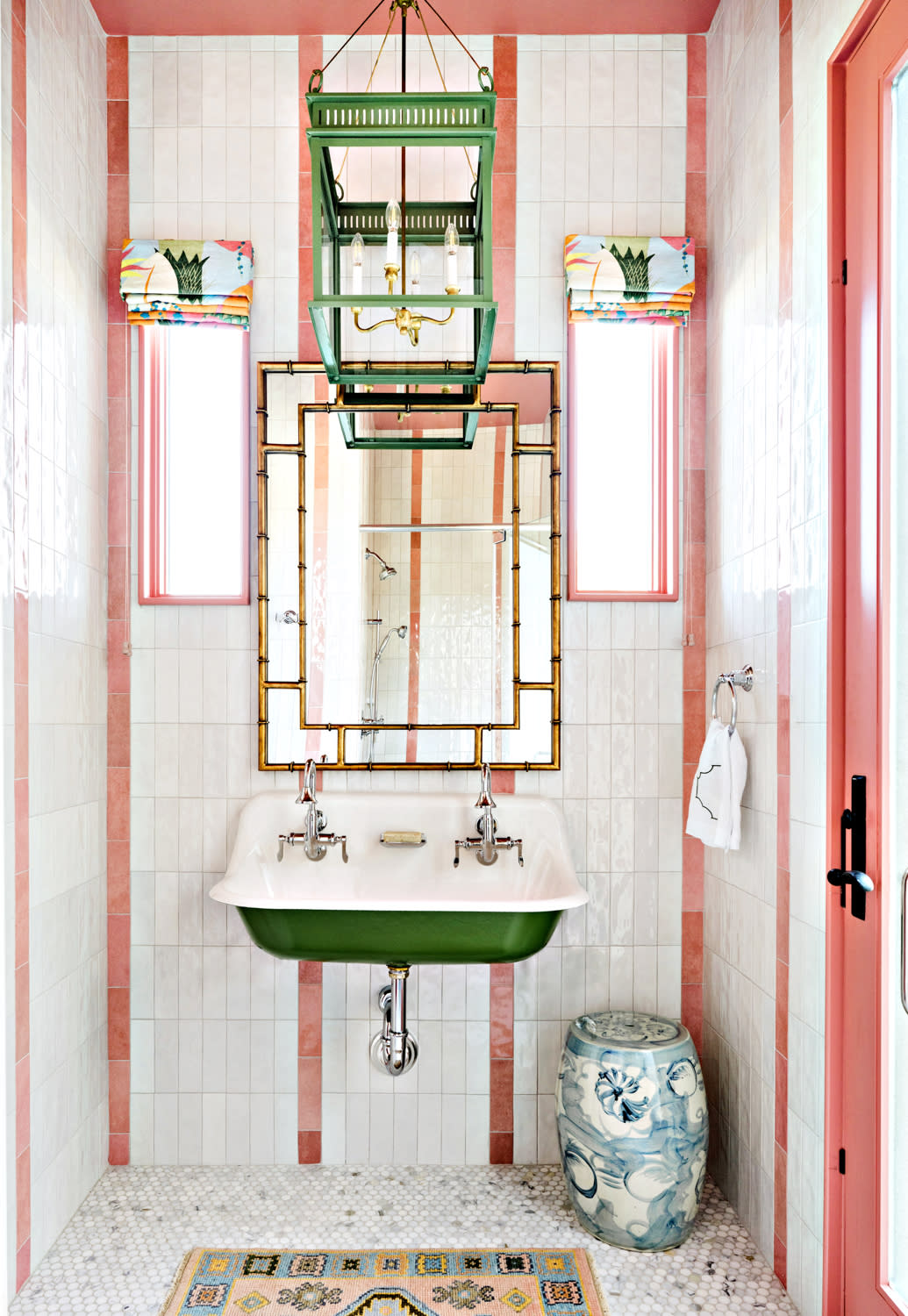 white and pink zellige tiles line the wall of this bathroom with a green trough sink