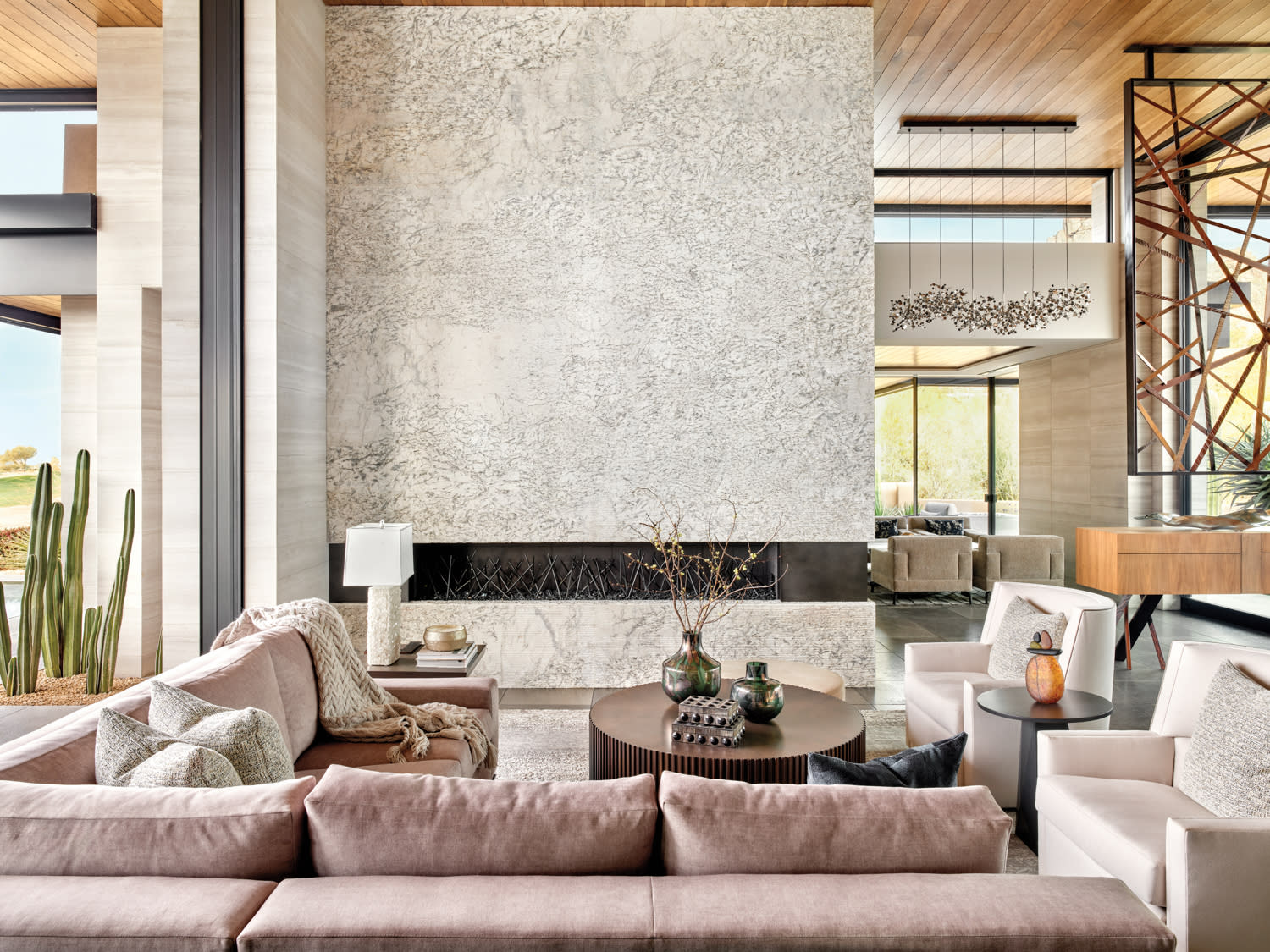 A stone fireplace sits in front of a couch and two armchairs arranged around a round coffee table.