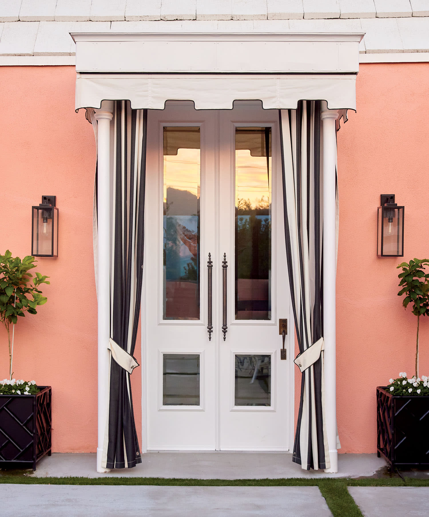 Elegant white French entry doors with black and white striped curtains on a peach home