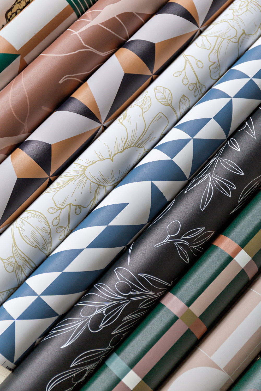 Rolls of graphic wallpaper in hues of white, cream, blue, orange and brown.