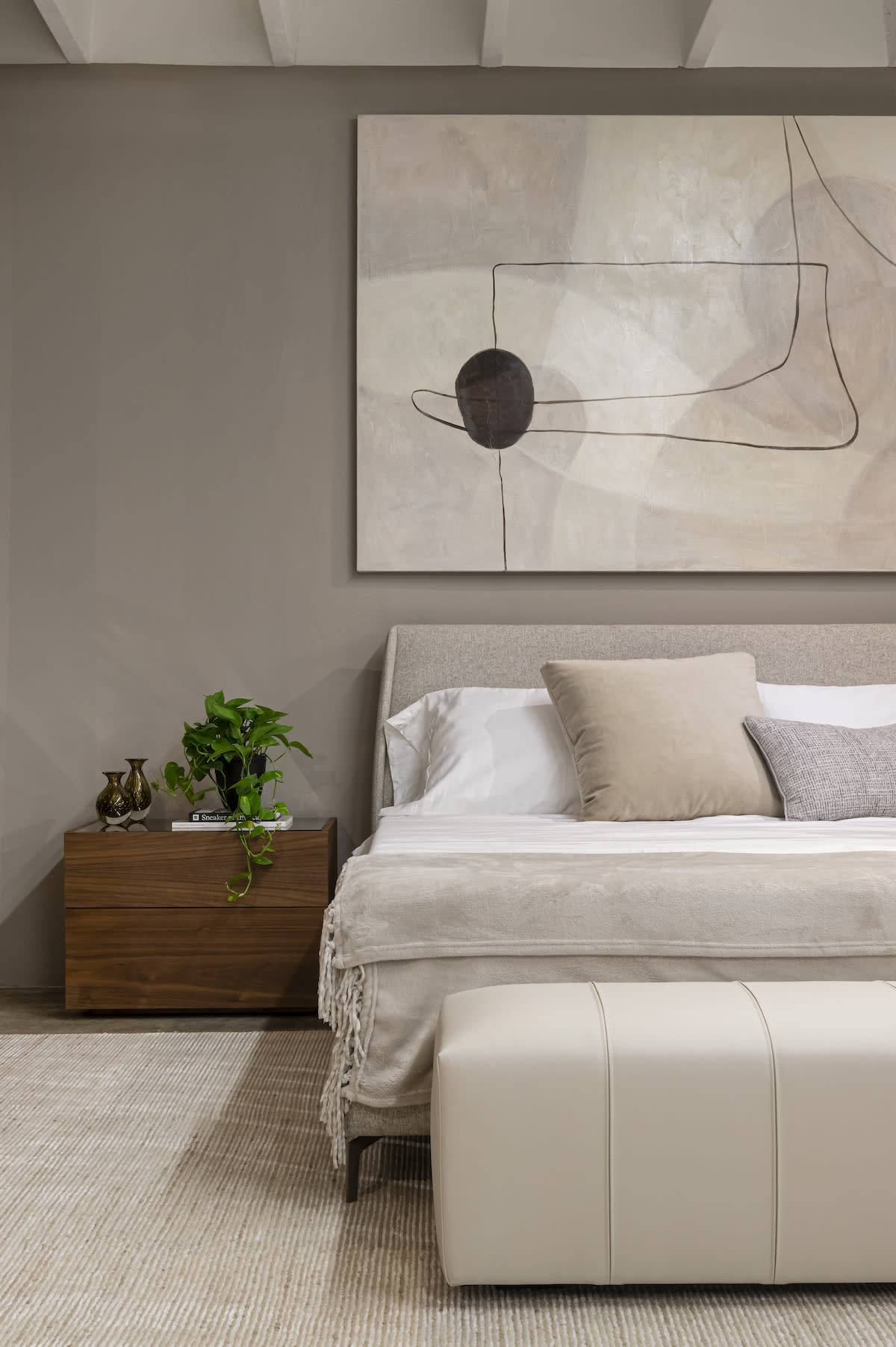 Brown night table, white bed, large wall art