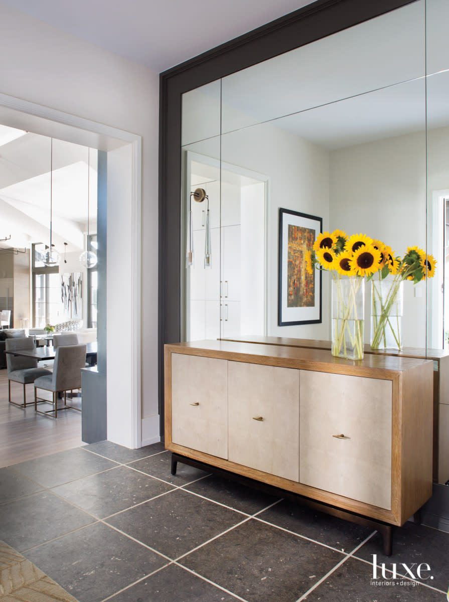 An entry features a mirrored wall and a light-wood console.