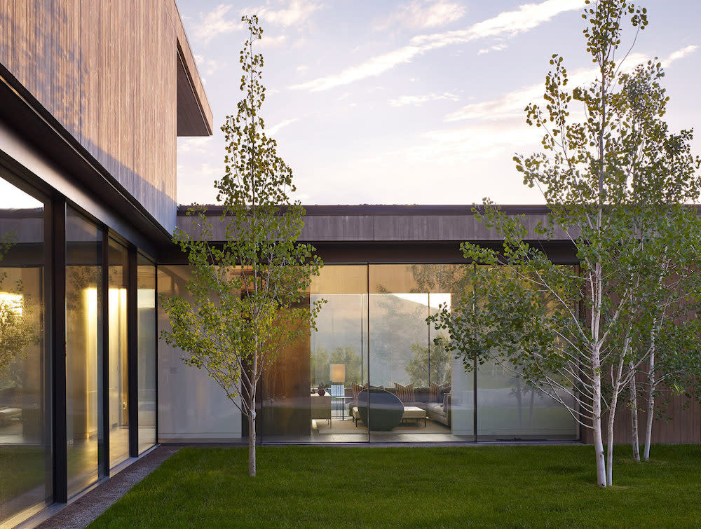 Floor to ceiling windows allow for a view of the trees in the grassy courtyard area