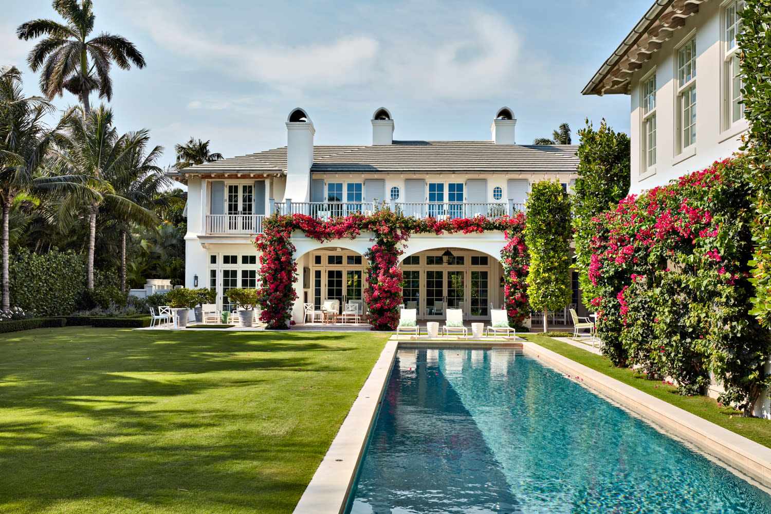 A large white house with a swimming pool and a well-maintained lawn.