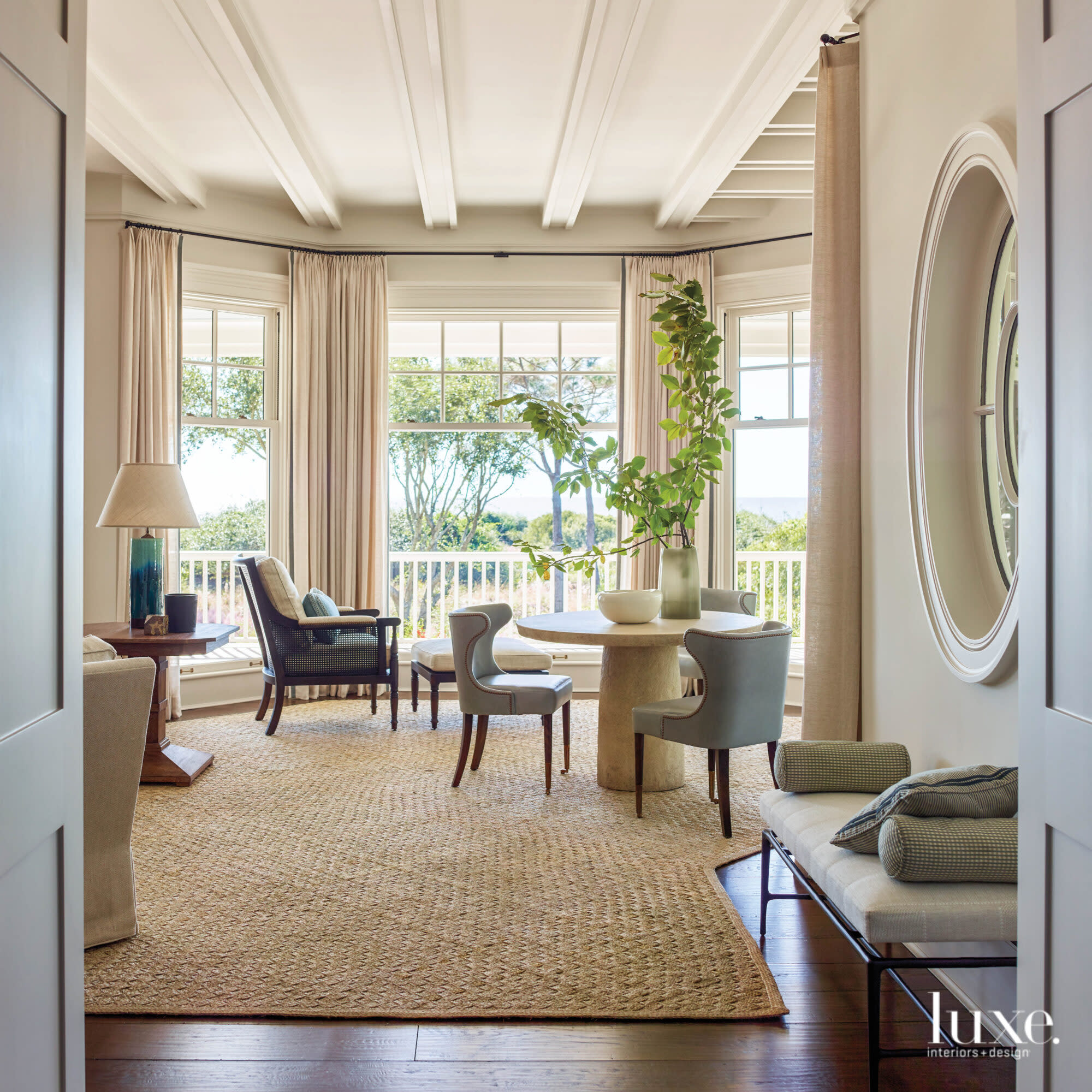 Living room with bay window, round game table, decorative oval window and paneled ceiling
