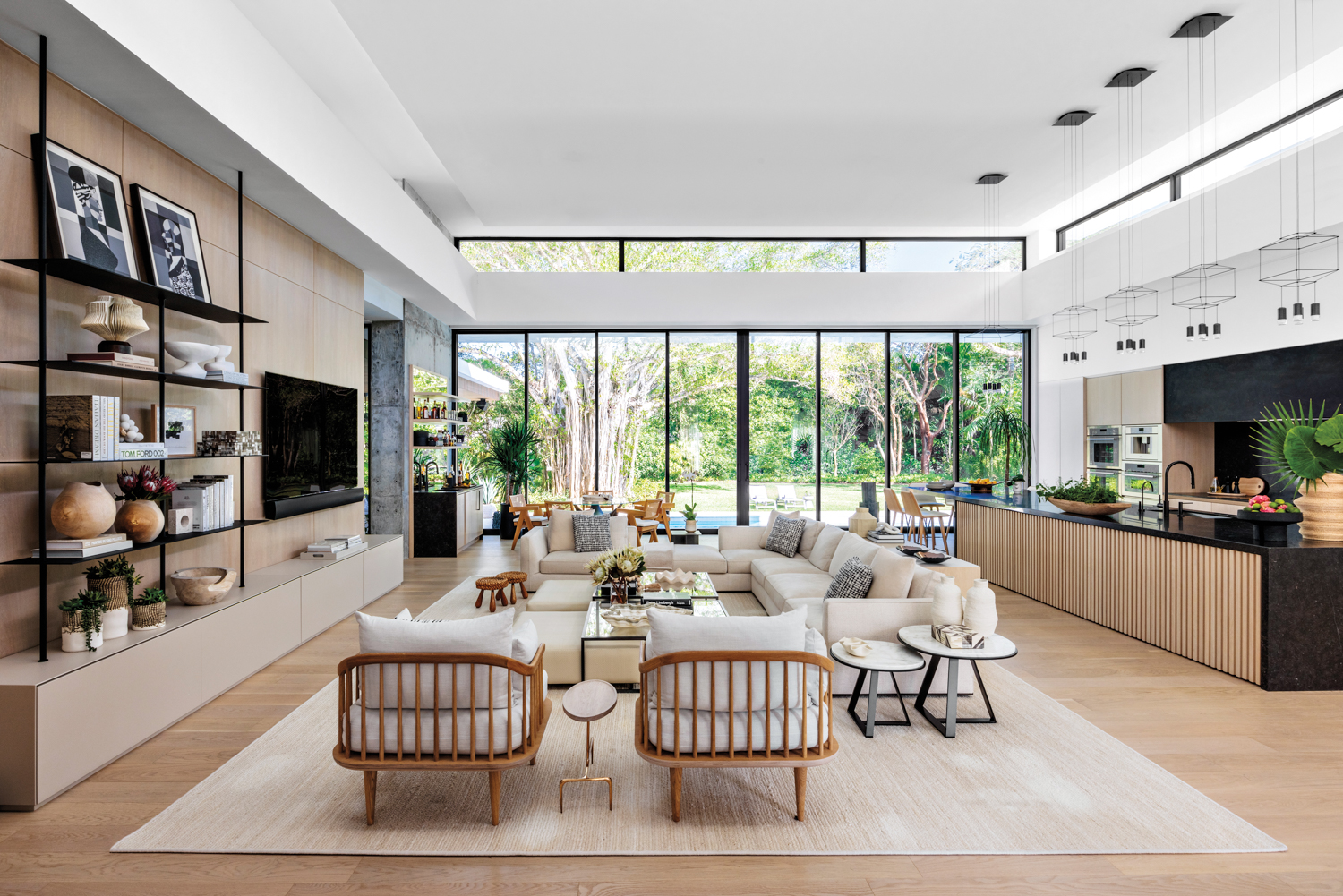 living area with cream-colored armchairs, sectional, rug and ottomans facing wood built-in