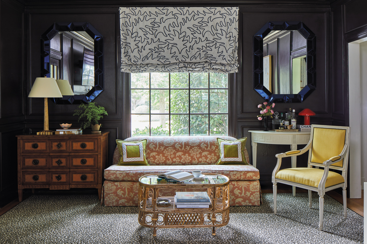 Sofa in front of window framed by mirrors and different side tables in a black-painted living room