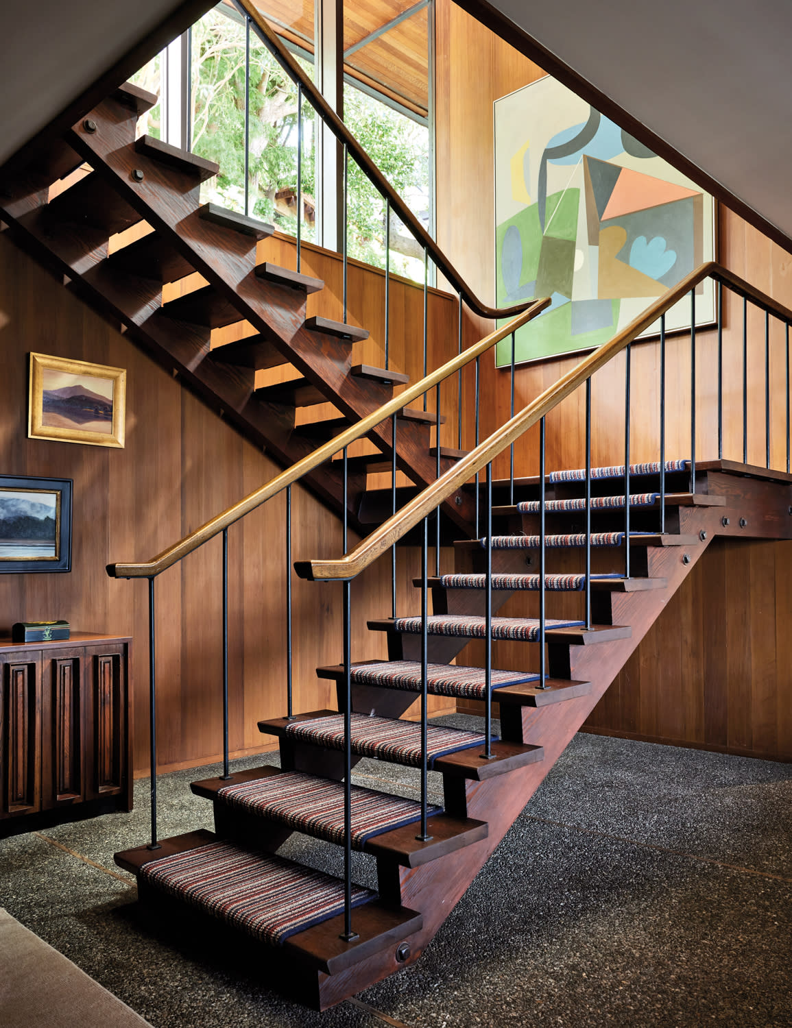 striped carpet treads line a staircase in a midcentury modern home