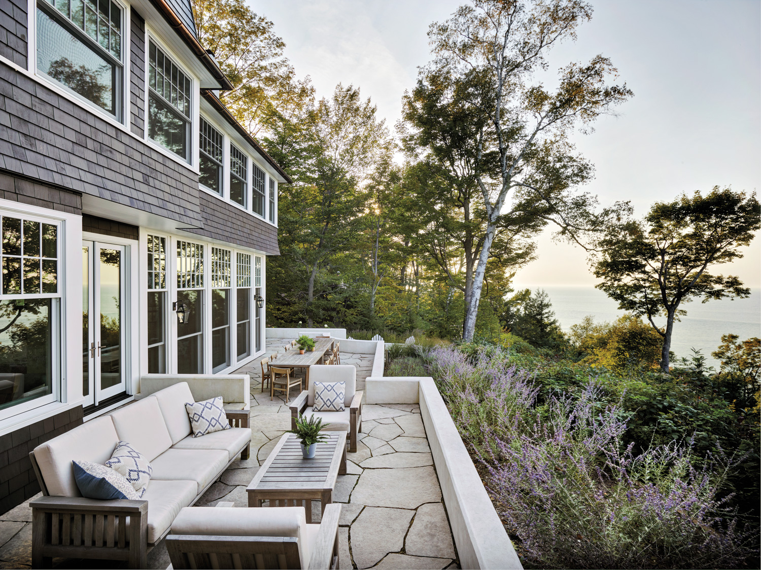 a stone back patio with a sofa, coffee table and chairs, as well as a dining area