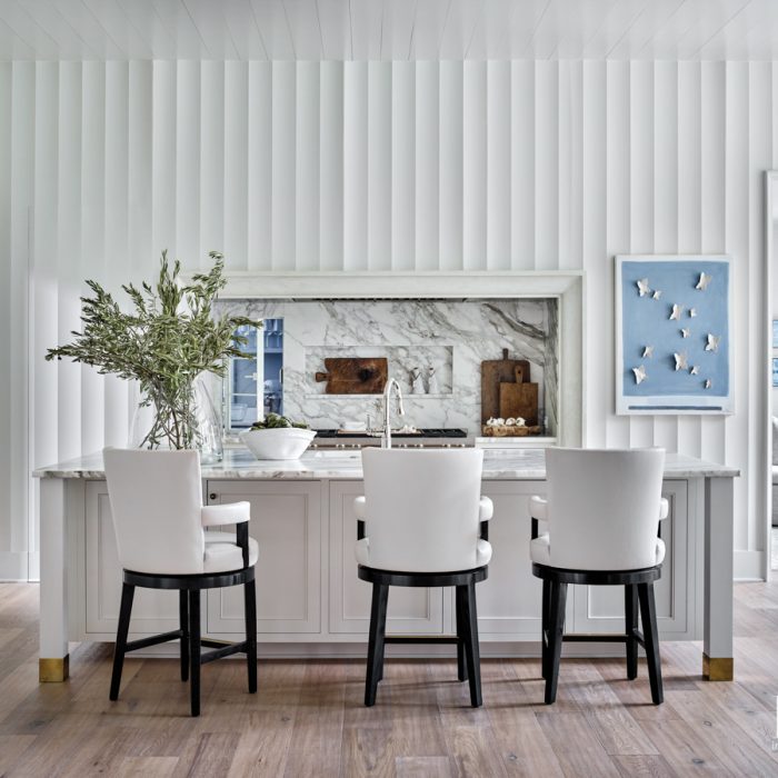 For the kitchen, the design team created a dimensional feature wall complemented by a Calacatta Gold marble backsplash--to which they added a subtle pass-through to the scullery beyond. Mauney completed the look with a Caroline Boykin mixed-media work from Anne Neilson Gallery and a trio of leather-covered counter stools by A. Rudin. Charlotte design