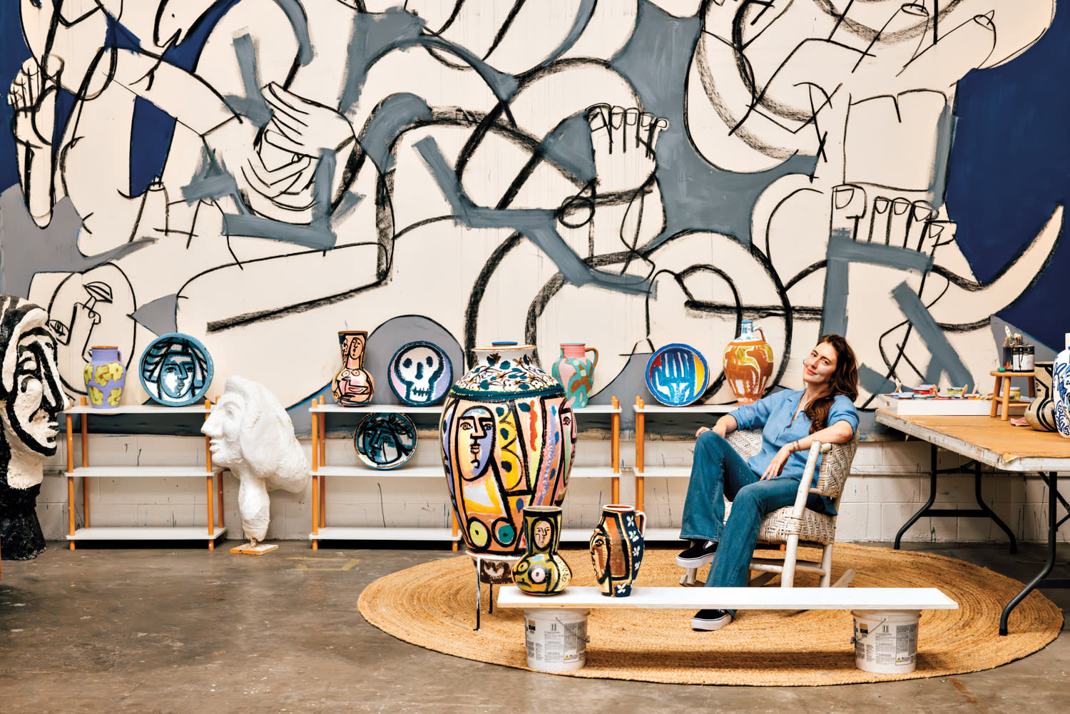 America Martin seated in front of one of her giant figurative paintings