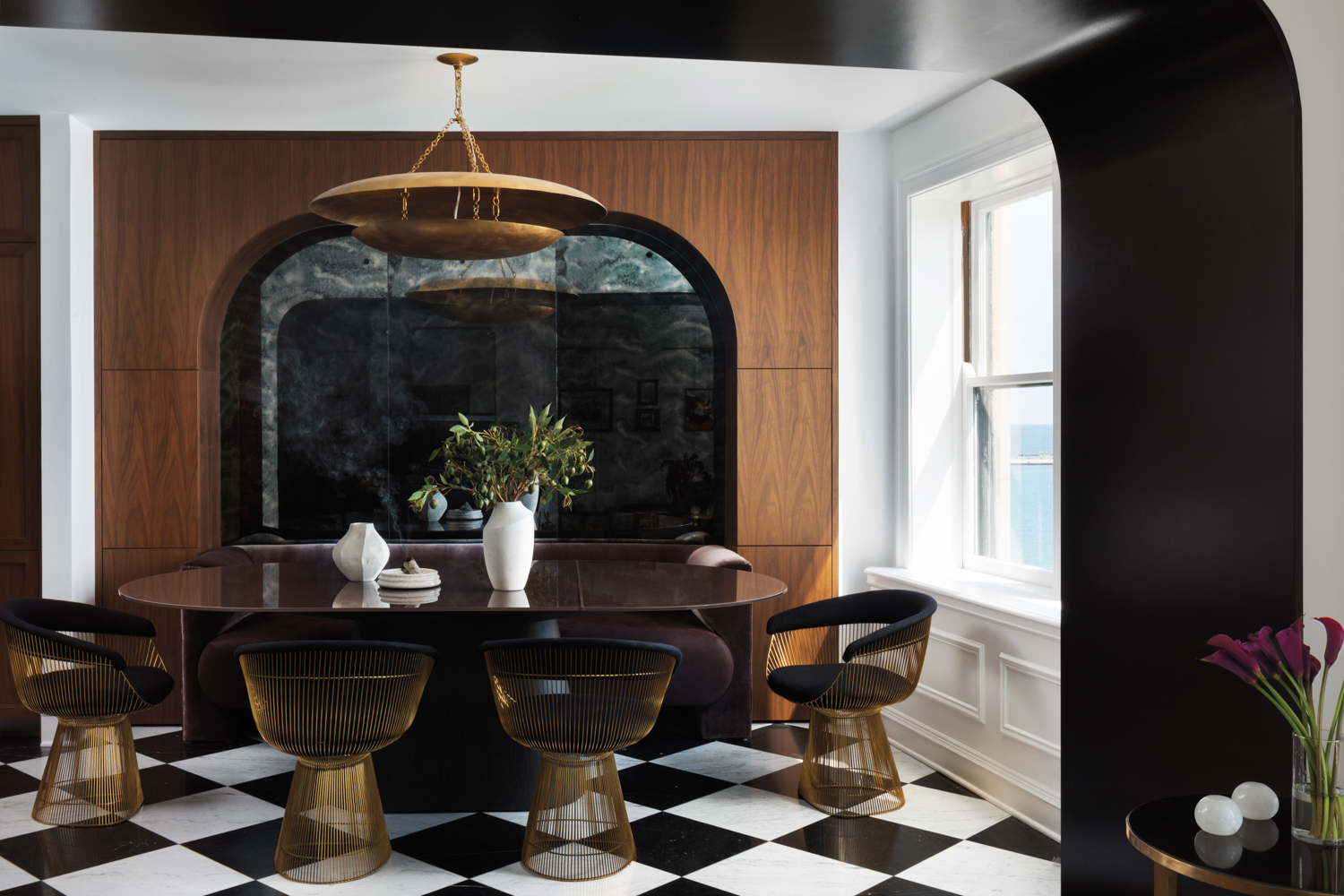 dining room with black-and-white checkerboard flooring, banquette and midcentury modern chairs