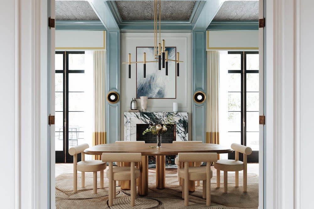 Blue-walled dining room with wooden table, blue beams, marble fireplace, and gold chandelier.