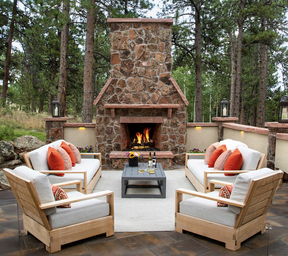 Outdoor patio with stone fireplace and comfortable seating area.